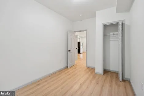 a view of a hallway with wooden floor and closet