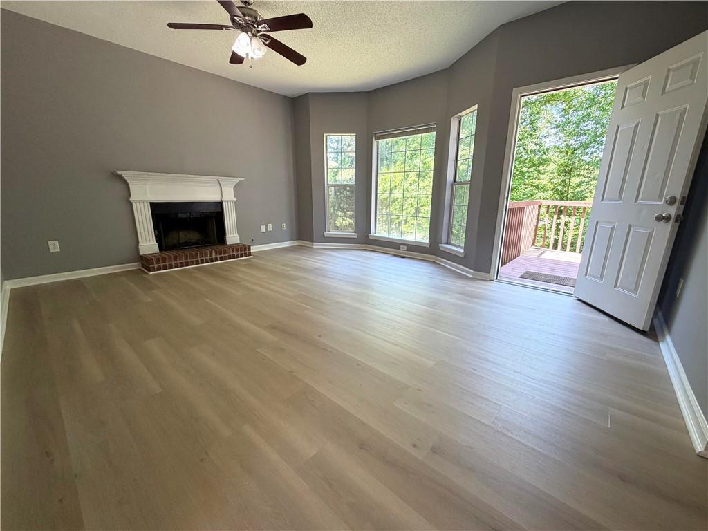 2205 Springer Walk Lawrenceville, GA 30043 - Photo 9 of 26 an empty room with wooden floor fireplace and windows
