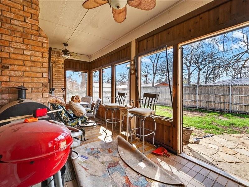 1704 South Bowen Road Pantego, TX 76013 - Photo 37 of 37 Enclosed patio featuring a brick accent wall, wood paneling, multiple windows, and a tiled floor