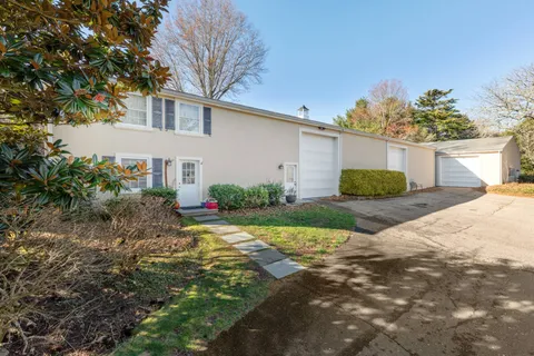 a view of a house with a small yard and a large tree