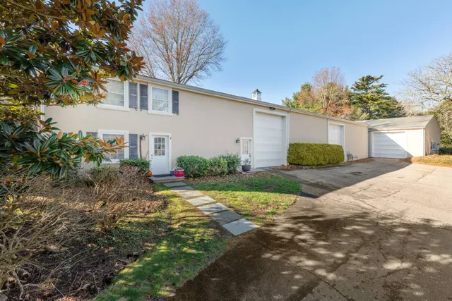 a view of a house with a small yard and a large tree