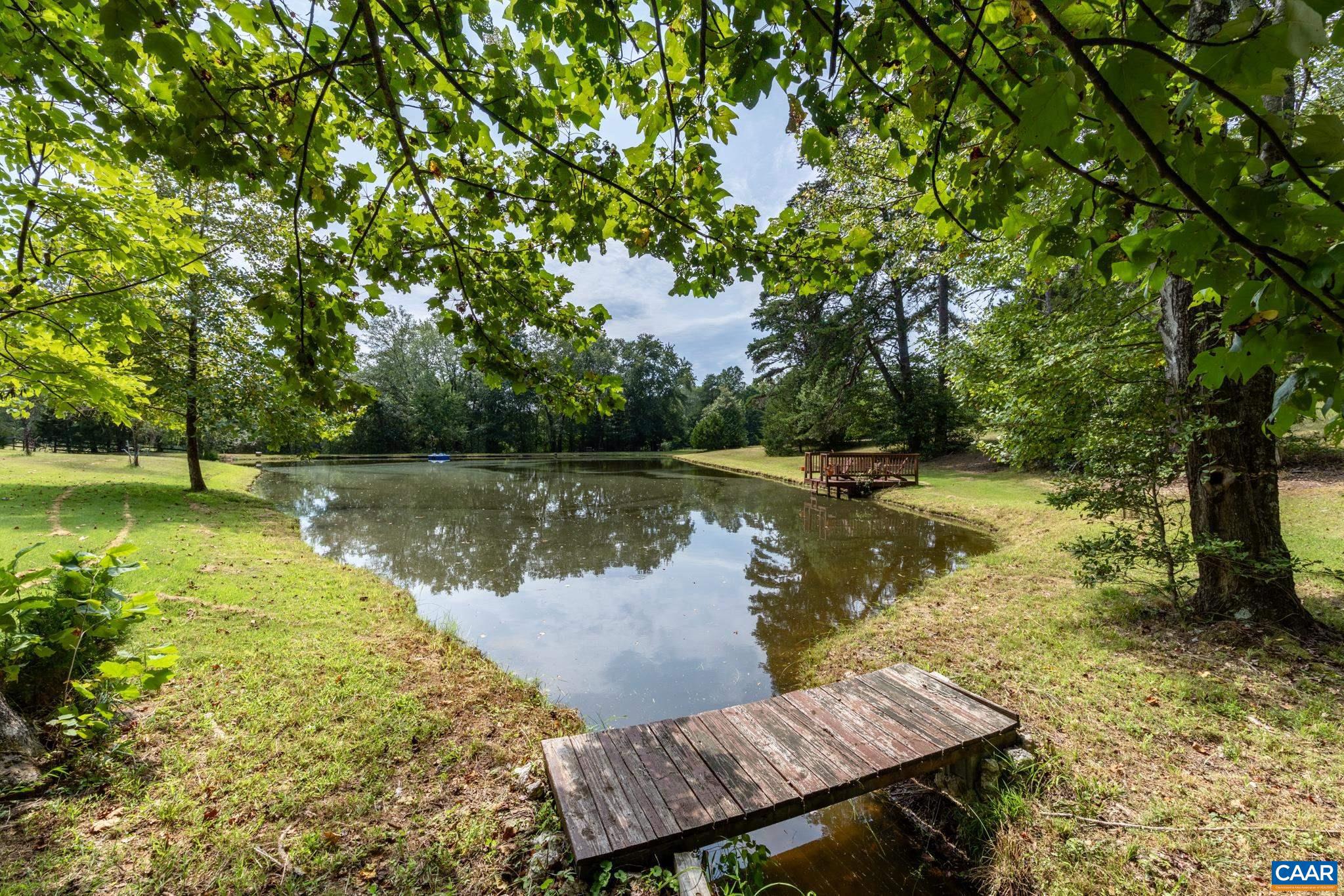 1128 Beaverdam Road Keswick, VA 22947 - Photo 22 of 74 a view of a lake with a bench and trees