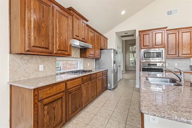 a kitchen with stainless steel appliances granite countertop a sink stove and cabinets