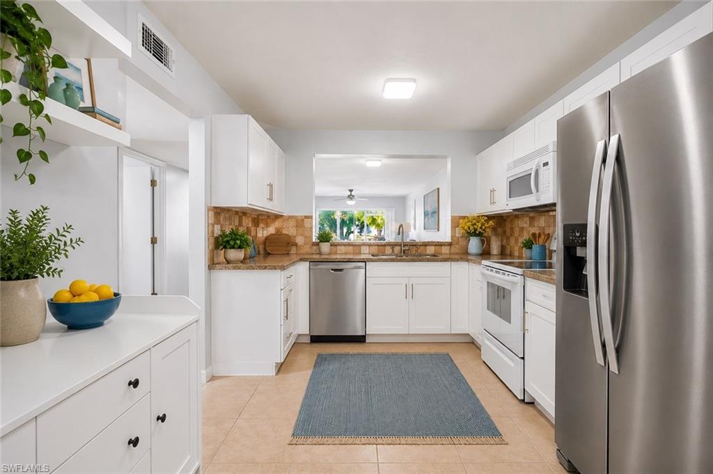 a kitchen with a refrigerator and white cabinets