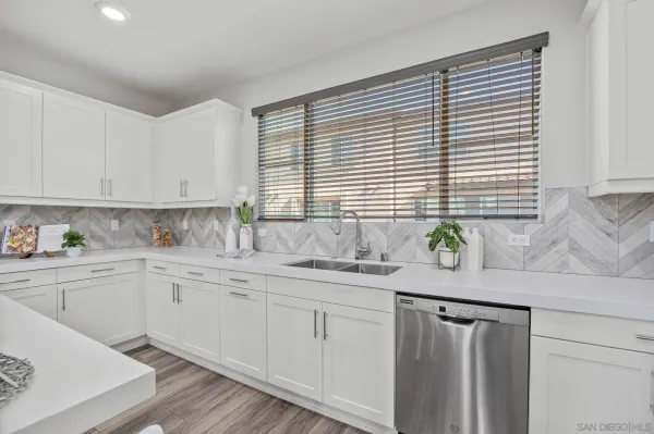 a kitchen with granite countertop white cabinets white appliances a sink and a window