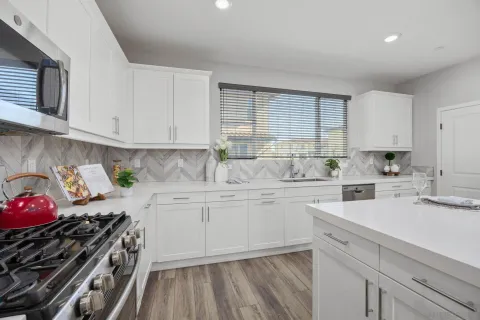 a kitchen with sink a stove and white cabinets
