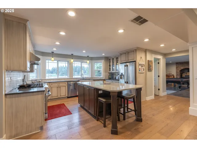 a kitchen with stainless steel appliances kitchen island granite countertop a table chairs sink and cabinets