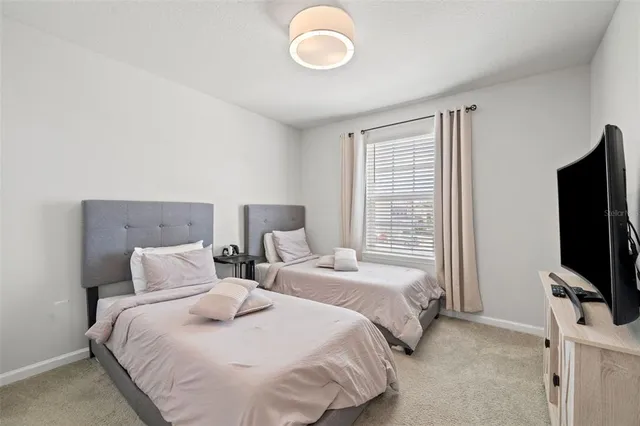 a bedroom with two beds and a flat tv screen on a dresser