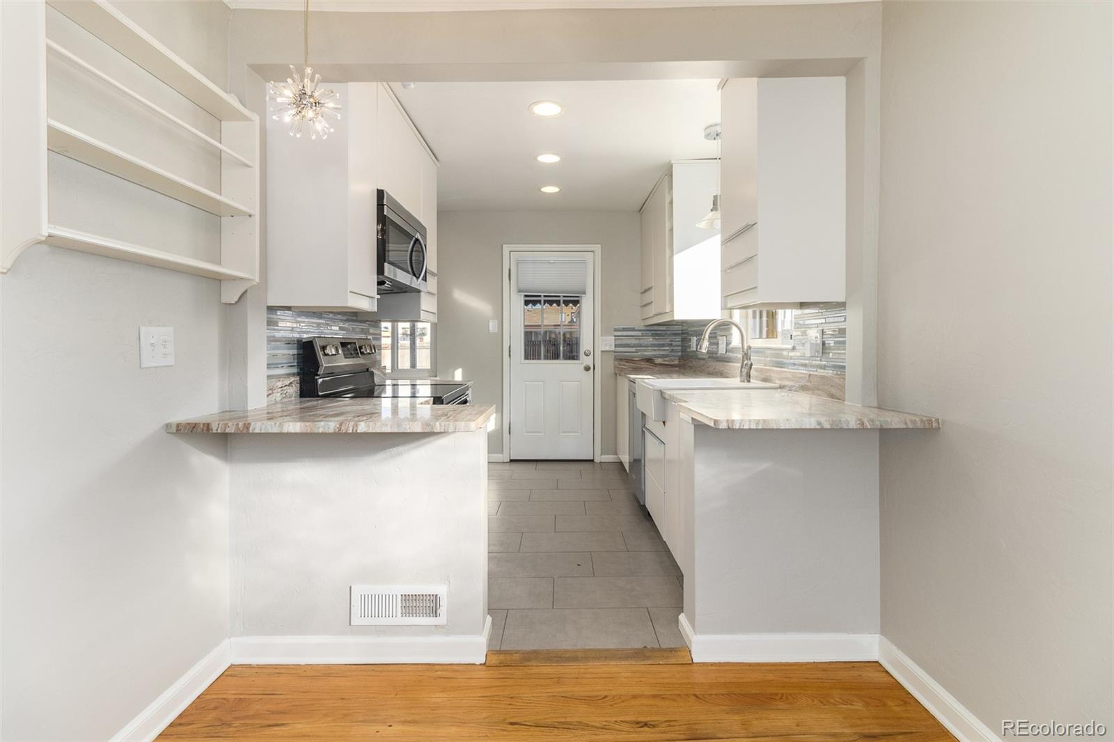 3040 Cook Street Denver, CO 80205 - Photo 10 of 19 a large white kitchen with kitchen island a sink stainless steel appliances and cabinets