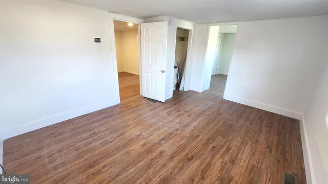 an empty room with wooden floor and white wall