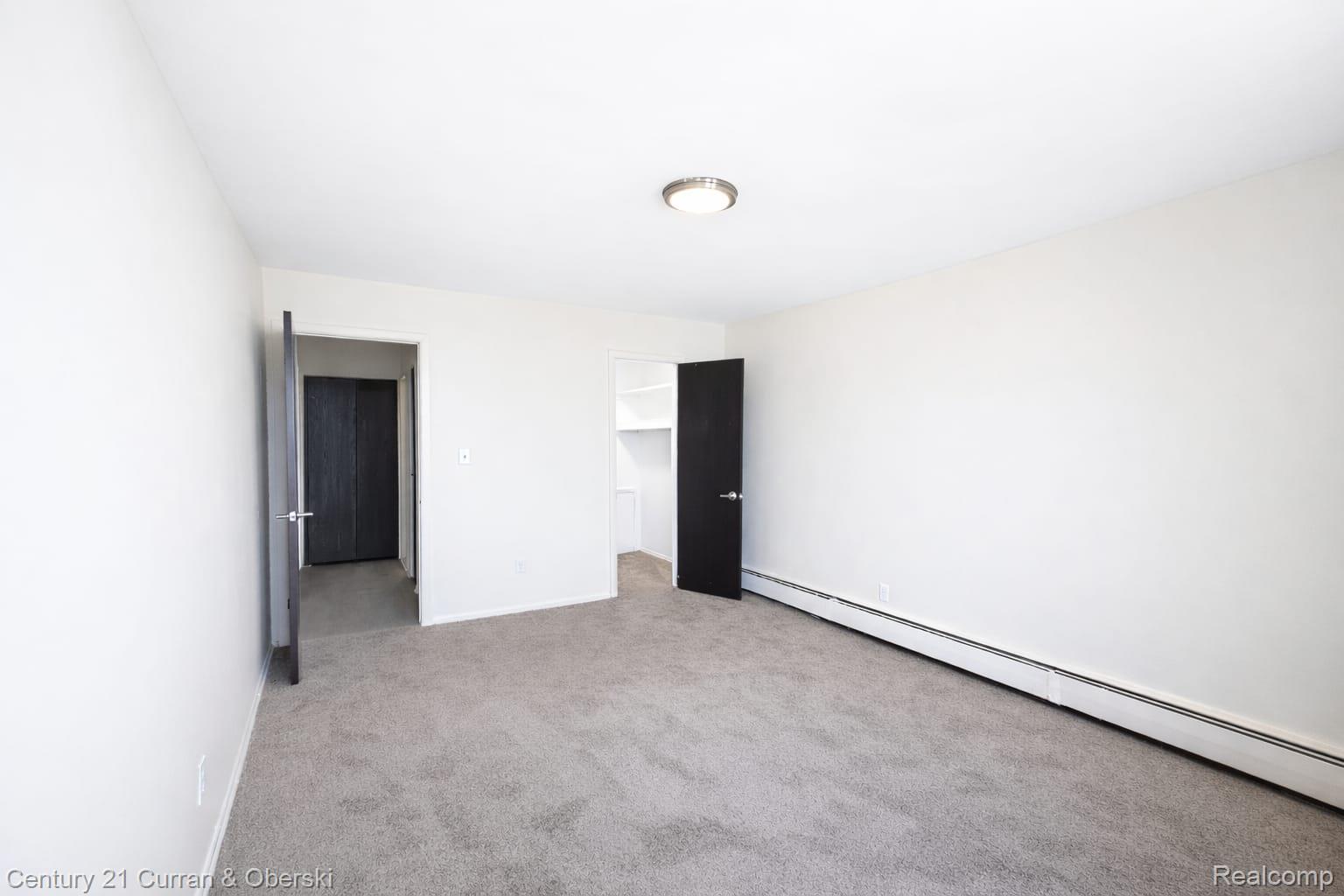 6015 Southfield Road, Unit 8 Detroit, MI 48228 - Photo 11 of 13 Unfurnished bedroom featuring baseboard heating, a spacious closet, and light carpet