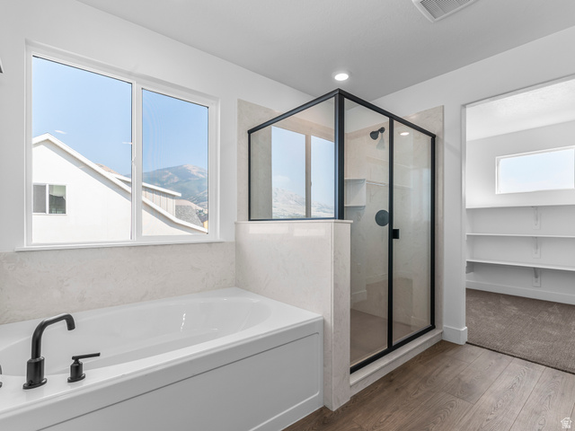 1380 West 2350 South, Unit 16 Perry, UT 84302 - Photo 30 of 34 Soaking tub with matte black fixtures, an enclosed glass shower with black framing, wood-finish flooring, and a large window