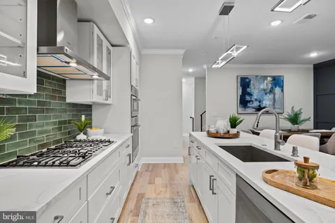 a kitchen with stainless steel appliances a refrigerator a stove a sink dishwasher with a dining table and chairs