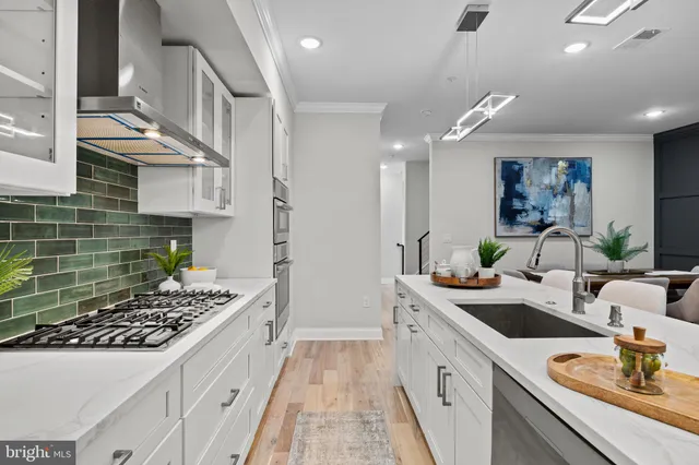 a kitchen with stainless steel appliances a refrigerator a stove a sink dishwasher with a dining table and chairs