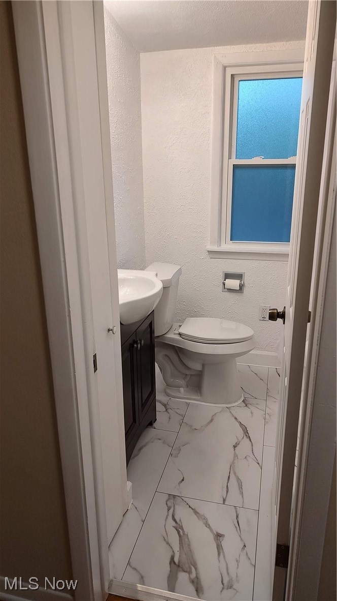 1750 Trinity Road Madison, OH 44057 - Photo 17 of 28 Bathroom with marble finish floors, vanity, toilet, and a textured wall