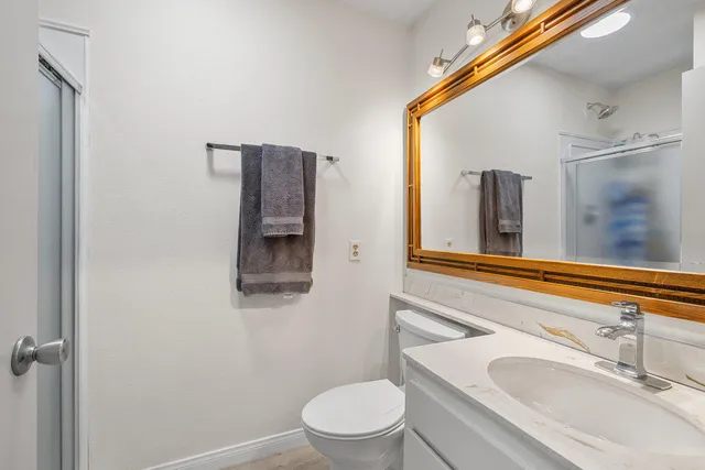 a bathroom with a granite countertop sink toilet and mirror