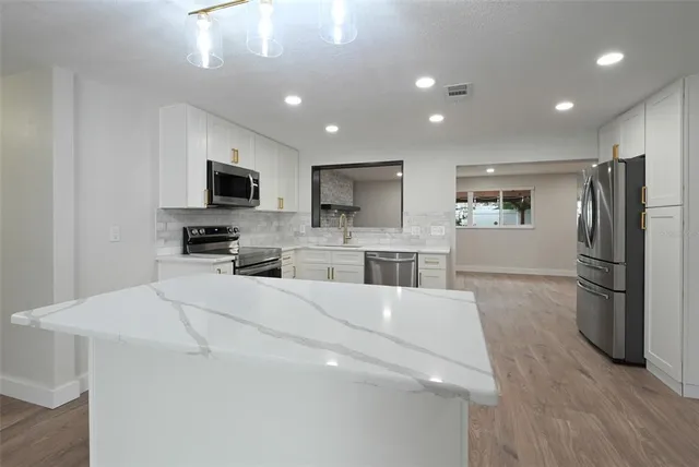 a large white kitchen with a refrigerator a stove top oven a sink dishwasher and wooden cabinets