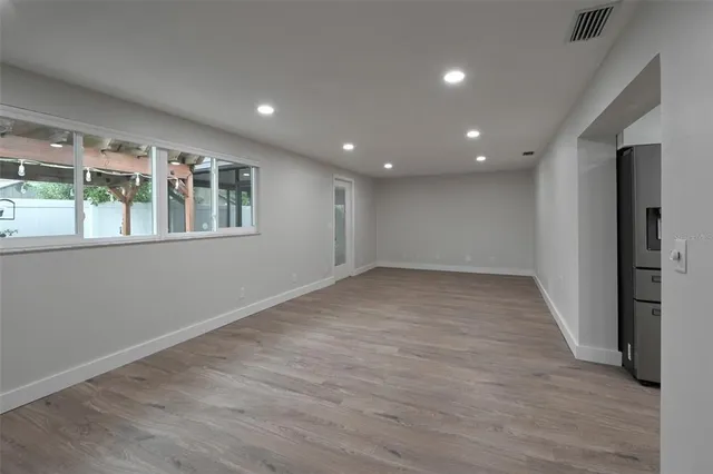 an empty room with wooden floor and windows