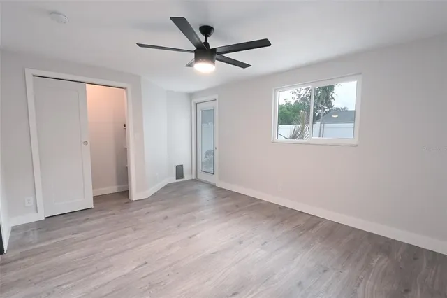 a view of an empty room with wooden floor and a window