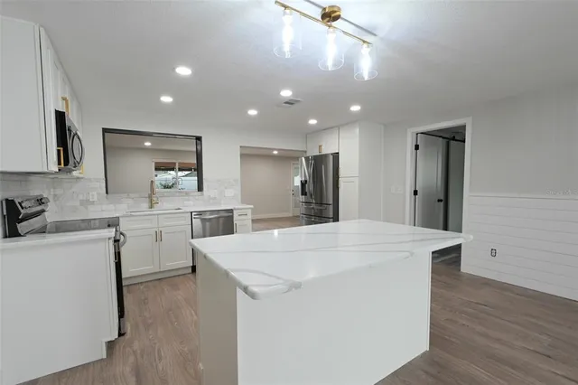 a large white kitchen with lots of counter space sink and appliances
