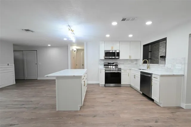 a large kitchen with a stove top oven a sink dishwasher a refrigerator and a oven with wooden floor