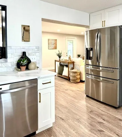 a kitchen with stainless steel appliances a refrigerator sink and white cabinets