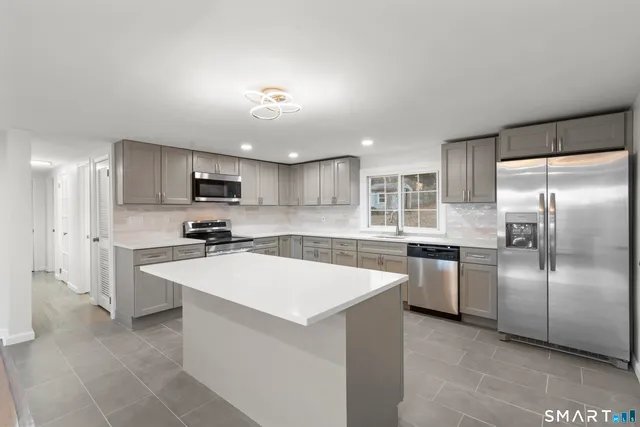 a large kitchen with kitchen island a sink stainless steel appliances and cabinets