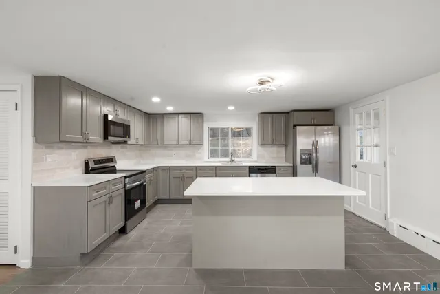 a large kitchen with kitchen island a sink stainless steel appliances and cabinets