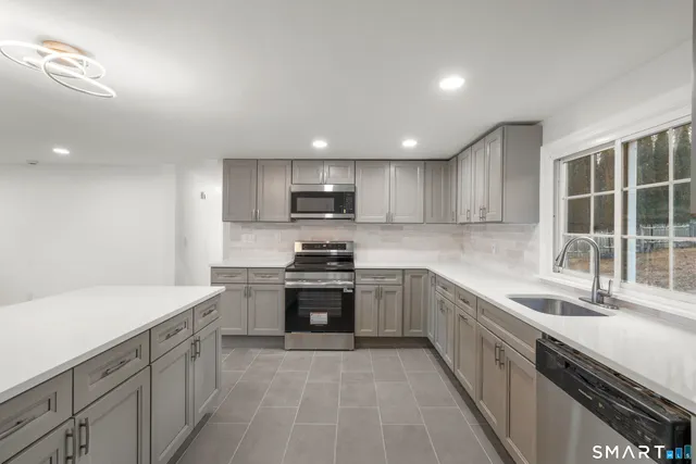 a kitchen with stainless steel appliances granite countertop a sink dishwasher stove and refrigerator