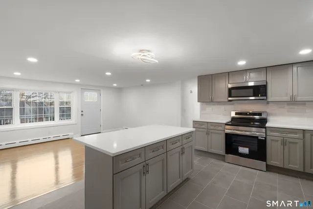 a large kitchen with stainless steel appliances granite countertop a sink and dishwasher a stove top oven with wooden floor