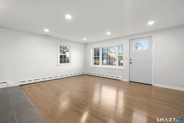 a view of an empty room with a window and wooden floor
