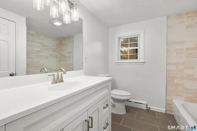 a bathroom with a sink a toilet a mirror and shower