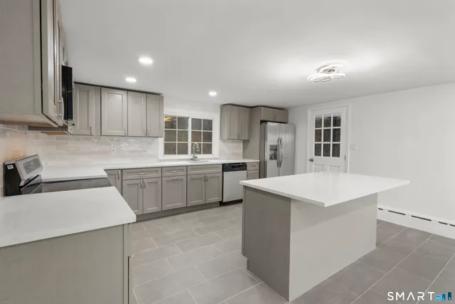 a kitchen with a sink a counter top space stainless steel appliances and cabinets