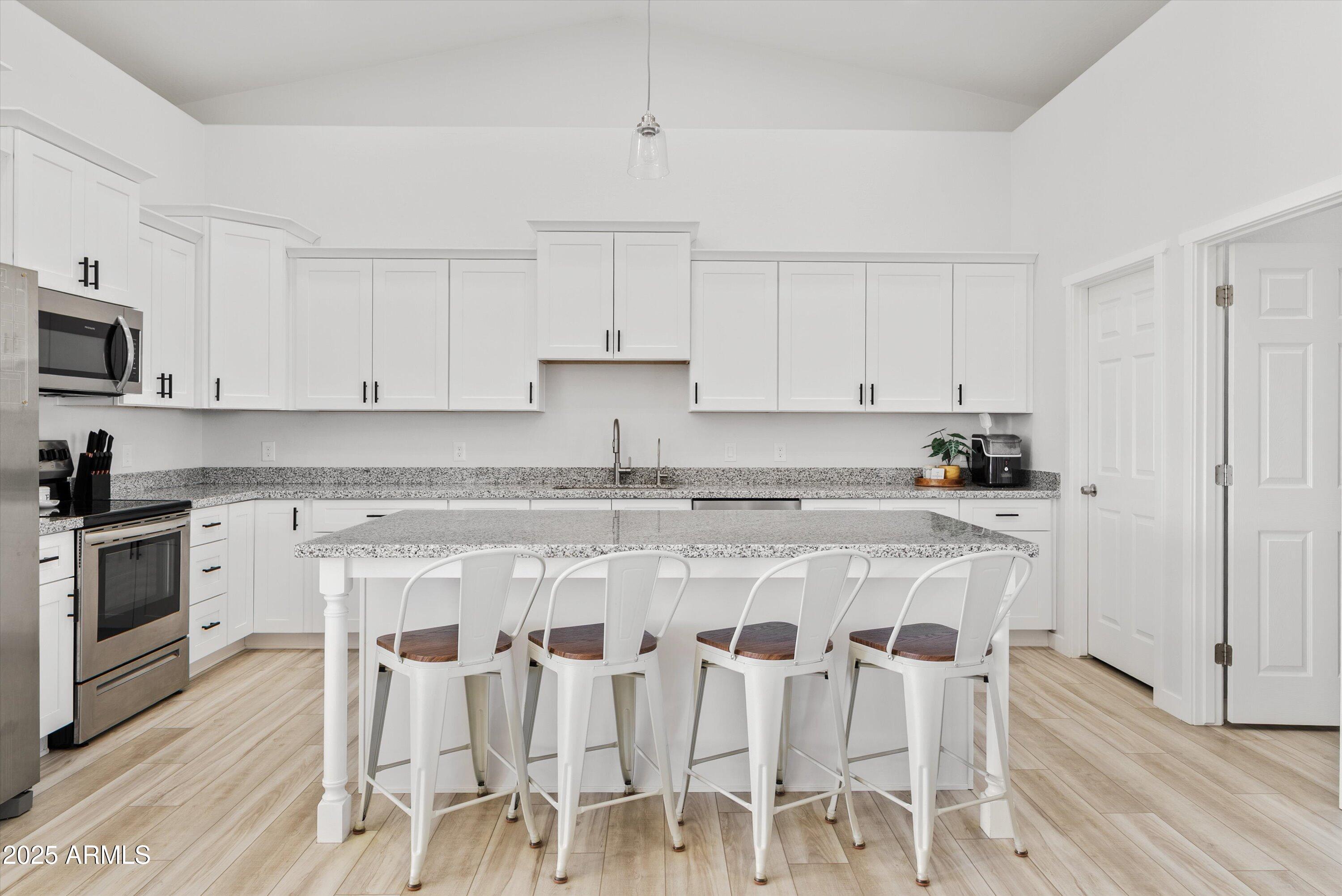 10473 East Dixie Road Florence, AZ 85132 - Photo 11 of 42 a white kitchen with wooden cabinets and stainless steel appliances