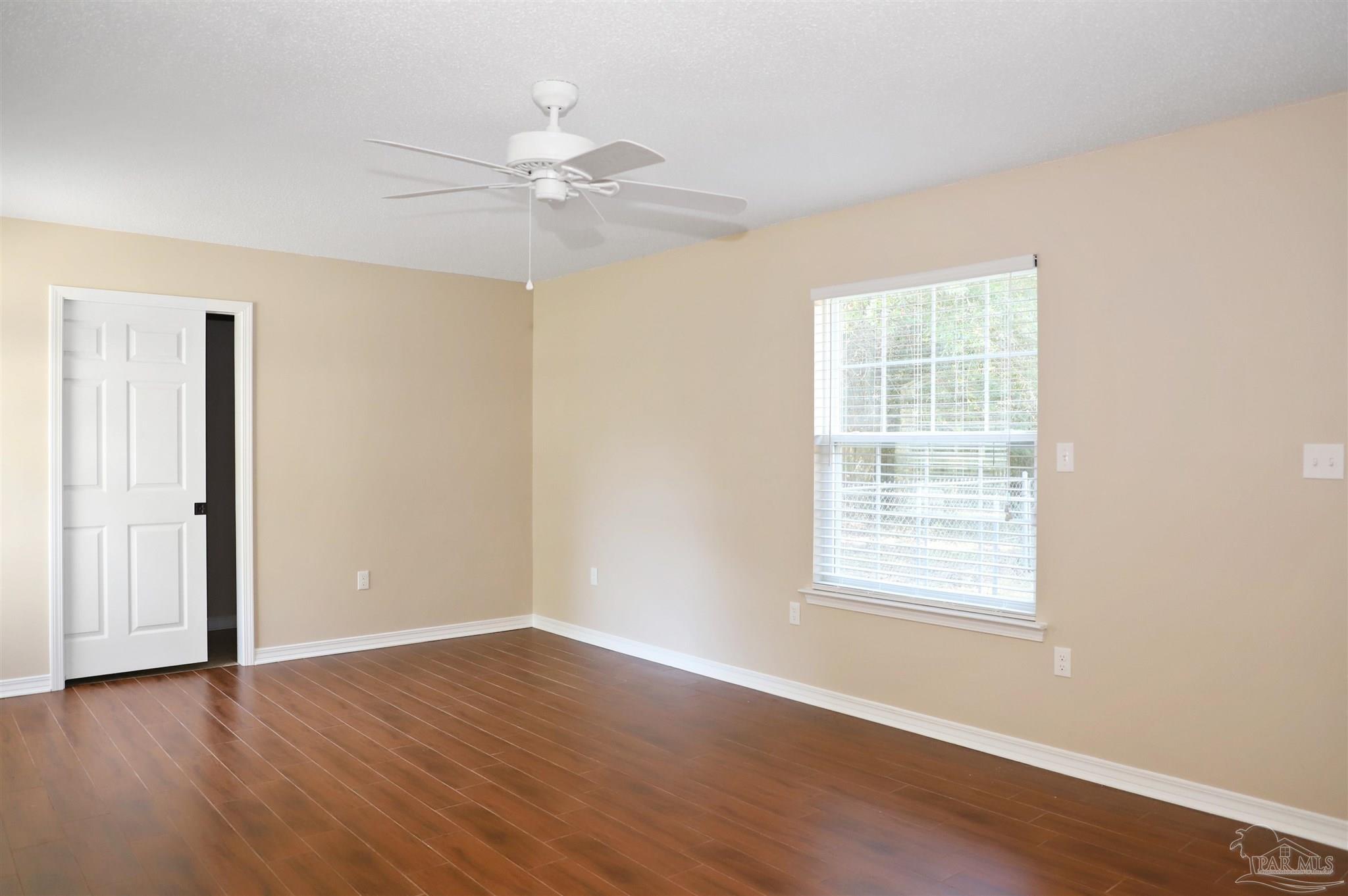 4454 Lyons Place Holt, FL 32564 - Photo 30 of 53 an empty room with wooden floor chandelier fan and windows