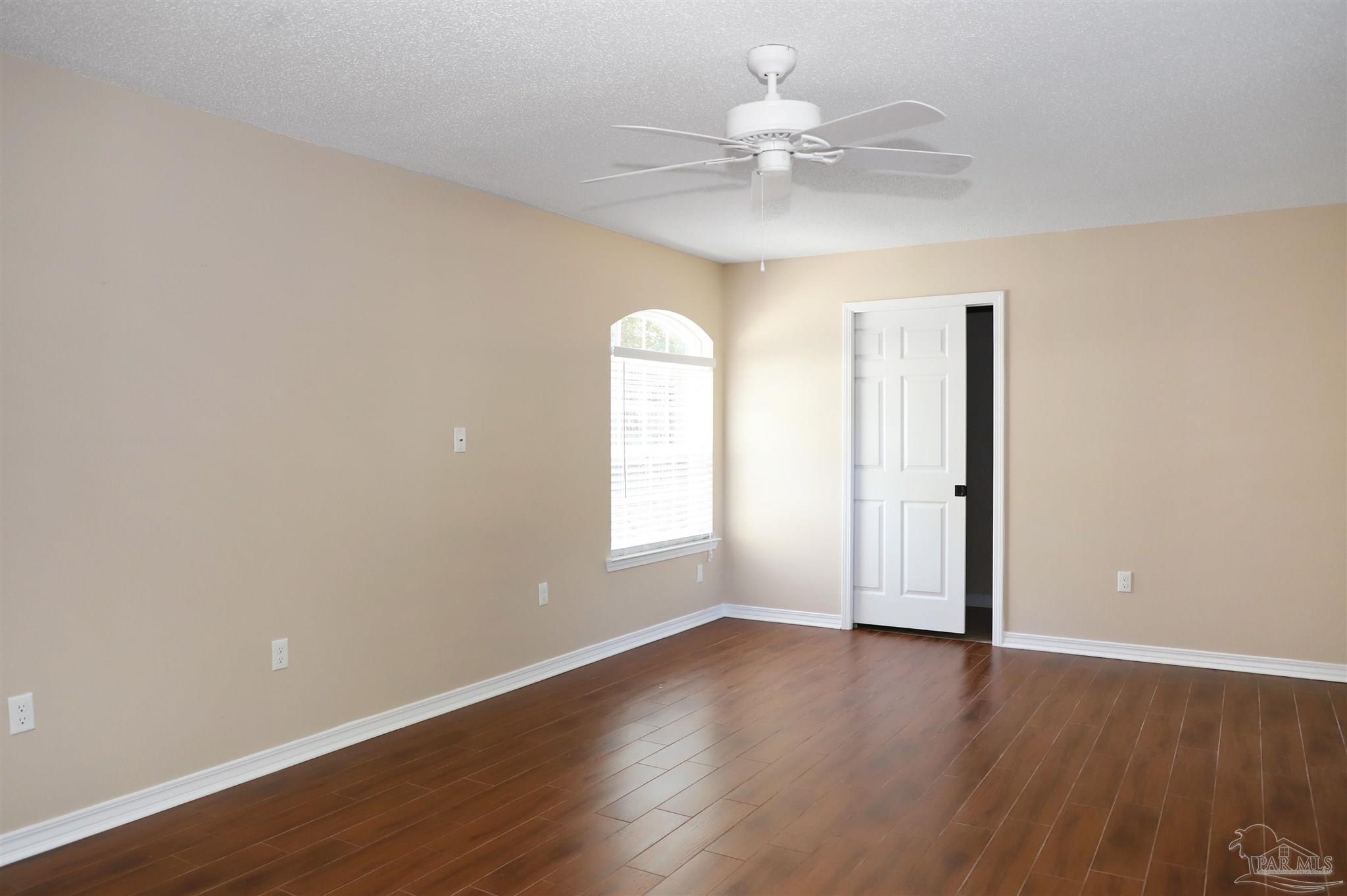 4454 Lyons Place Holt, FL 32564 - Photo 32 of 53 an empty room with wooden floor chandelier fan and window