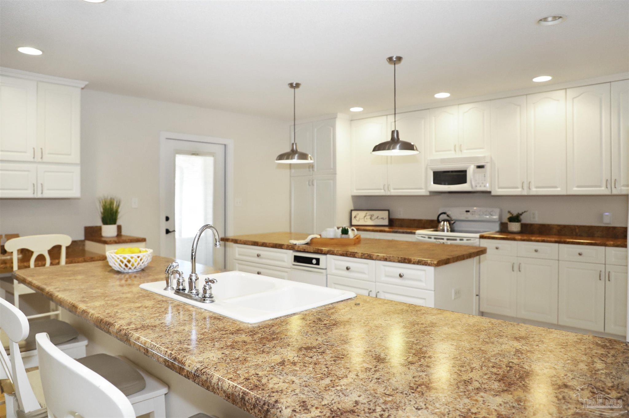 4454 Lyons Place Holt, FL 32564 - Photo 8 of 53 a kitchen with kitchen island granite countertop a sink a counter top space and cabinets