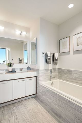 a spacious bathroom with a tub sink and mirror