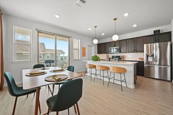 a kitchen with a refrigerator a dining table and chairs