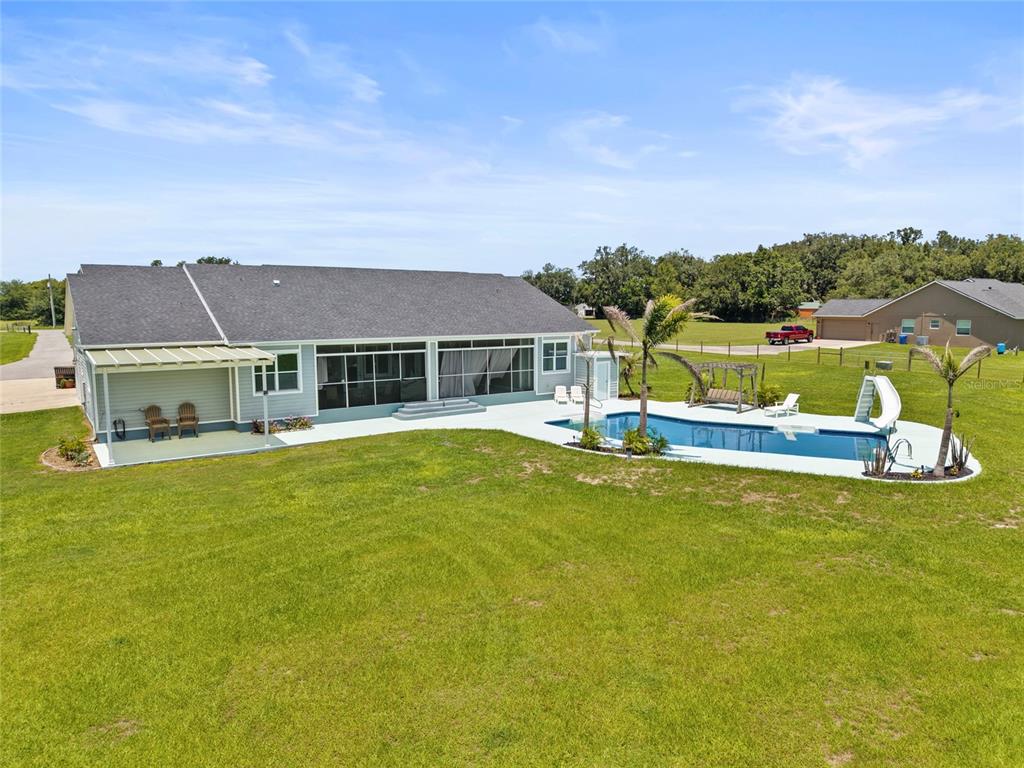 15710 Colding Loop Wimauma, FL 33598 - Photo 3 of 41 a view of a house with a big yard and a large pool with table and chairs next to a yard
