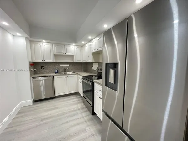 a kitchen with white cabinets and stainless steel appliances