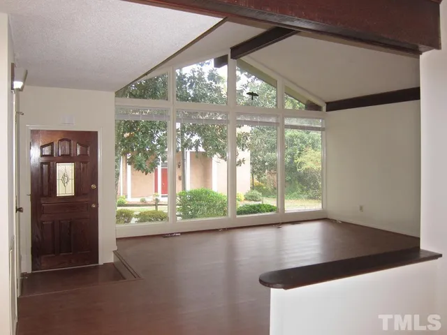 a view of empty room with floor to ceiling windows and wooden floor