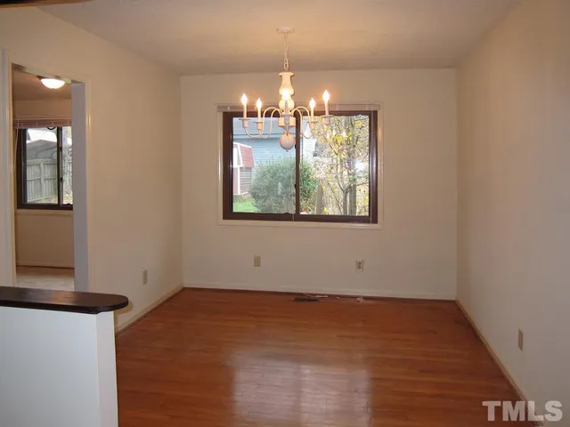en empty room with wooden floor and chandelier