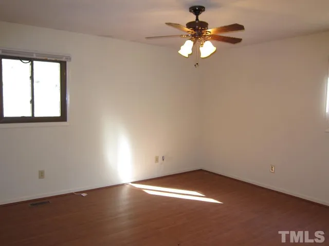 an empty room with a window and a chandelier fan