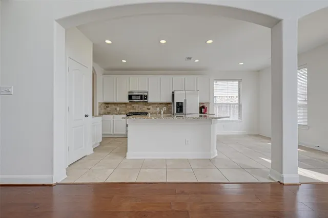 a large white kitchen with kitchen island sink refrigerator and white cabinets