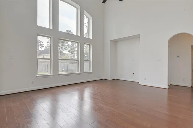 an empty room with wooden floor and windows