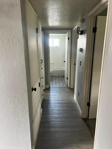 a view of a hallway with wooden floor and closet area