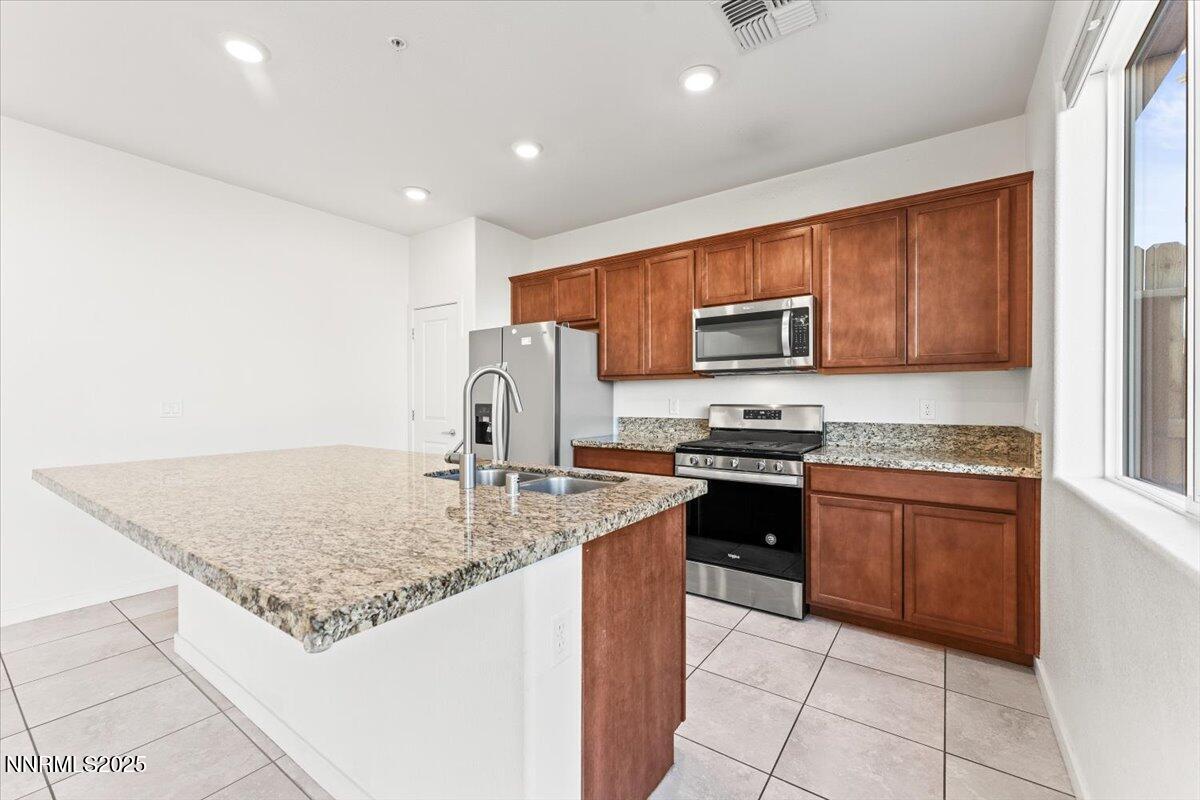 1048 Big Rock Loop Sun Valley, NV 89433 - Photo 5 of 25 a kitchen with stainless steel appliances granite countertop a stove top oven a sink dishwasher and a refrigerator with wooden cabinets