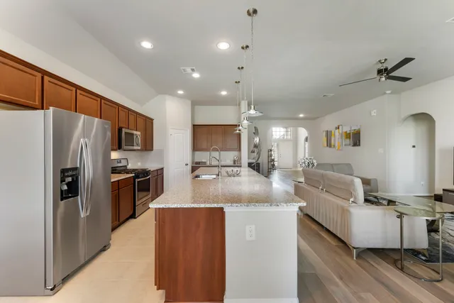 a large kitchen with stainless steel appliances kitchen island a large counter top a stove a refrigerator cabinets and living room view