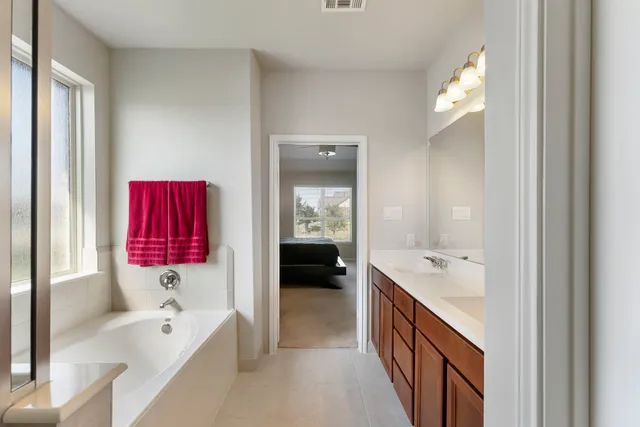 a en suite spacious bathroom with a double vanity sink a large mirror and shower